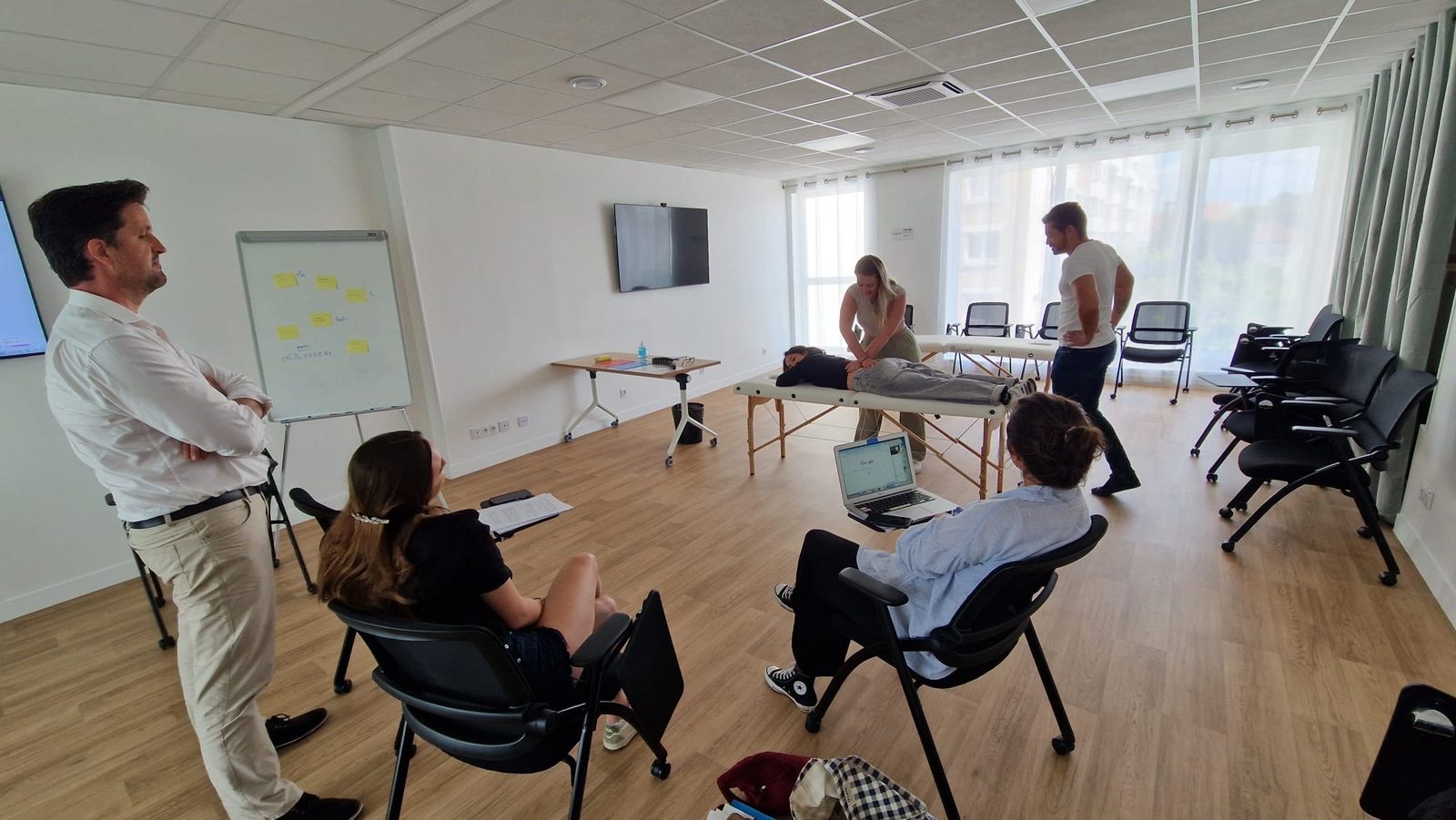 Mise en situation en travail pratique : démonstration d'une technique sur table d'ostéopathie observée par le groupe